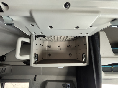 Volvo VNL64T860 cab interior showing open overhead storage box with empty aluminum compartment and mounting hardware.