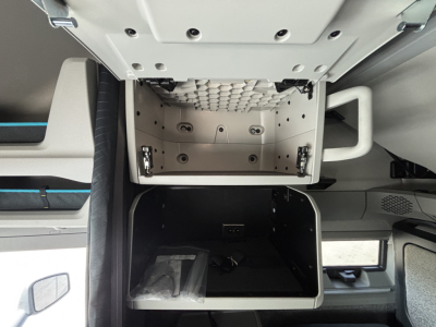 Volvo VNL64T860 sleeper cab interior showing open overhead storage and lower cabinet in-service with visible hinges and interior panels.