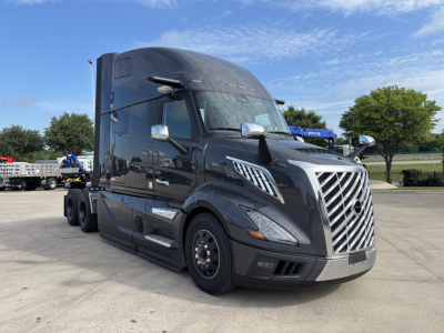 Volvo VNL64T860 tractor cab in dark gray, front angled view, chrome grille with vertical slats, daytime running lights, side mirrors, no visible text labels.