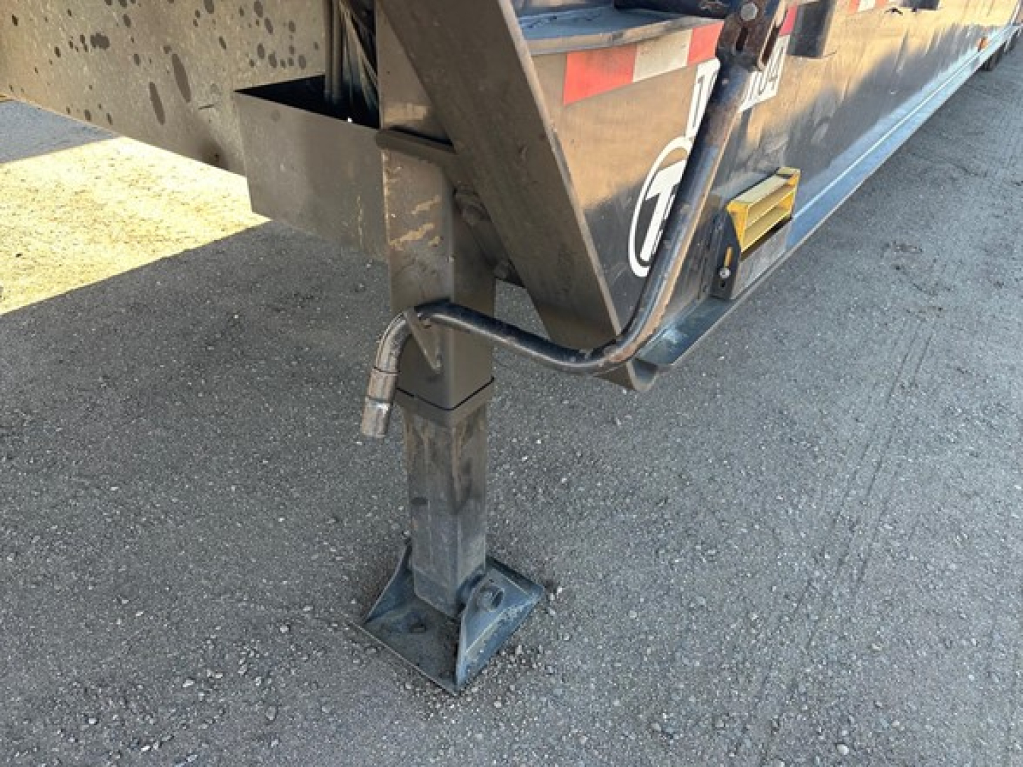 Trailer hitch with jack stand and wiring on Trail-Eze 40-ton hydraulic tail, showing stabilizing leg and deck hardware.