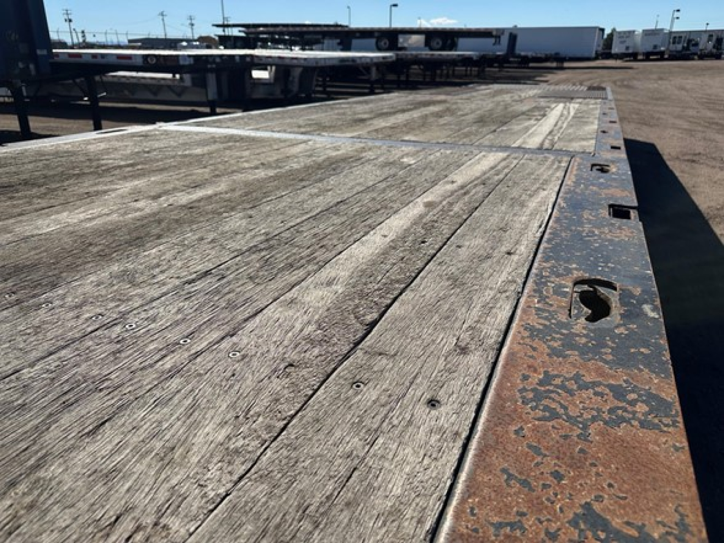 Trailer deck with weathered wooden planks and rusted edge metal, visible winch mounting area and upper deck trailer components.