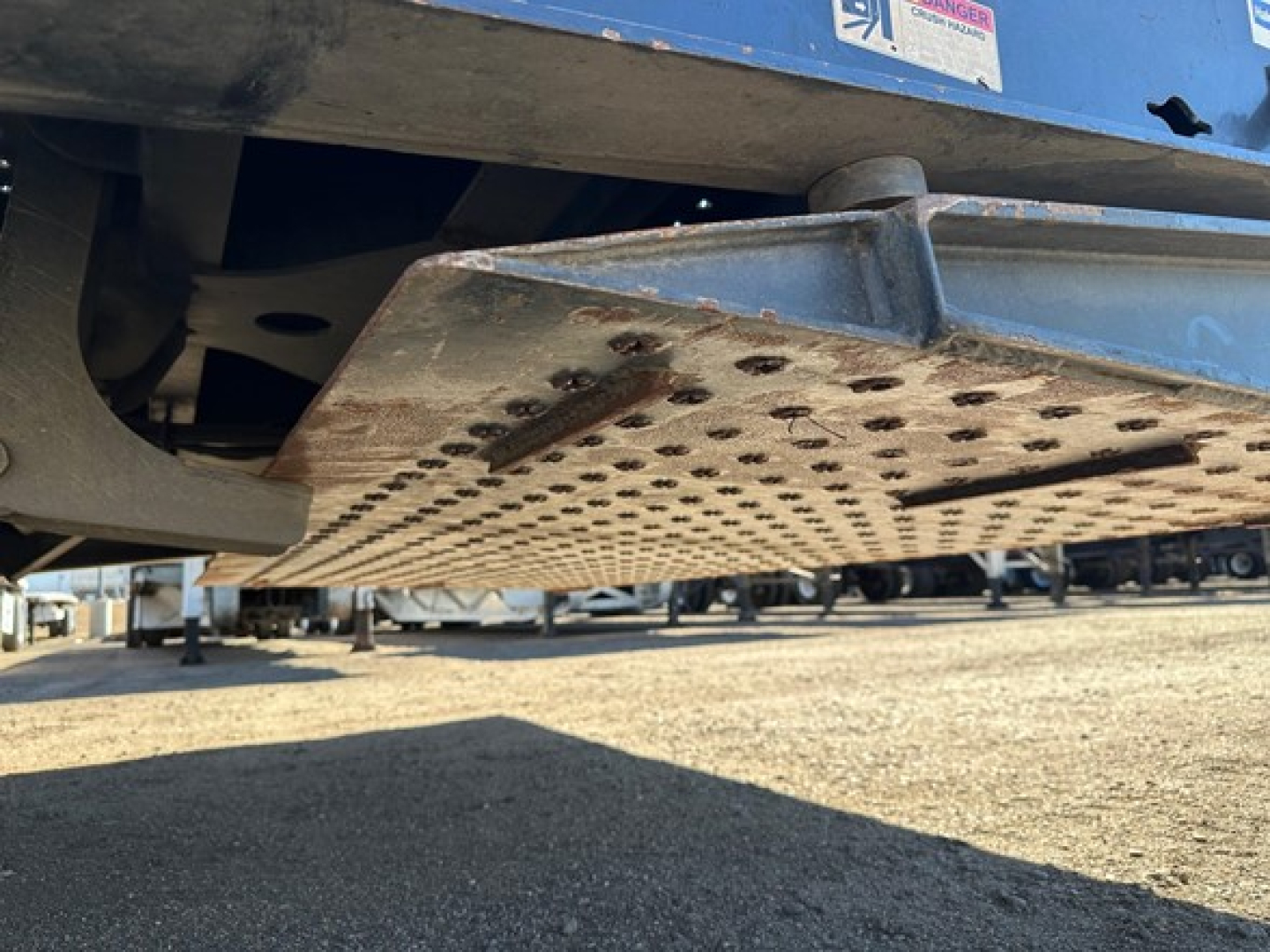 Trailer tail plate with perforated metal step and hydraulic landing gear visible under blue Trail-Eze 40-ton tail system