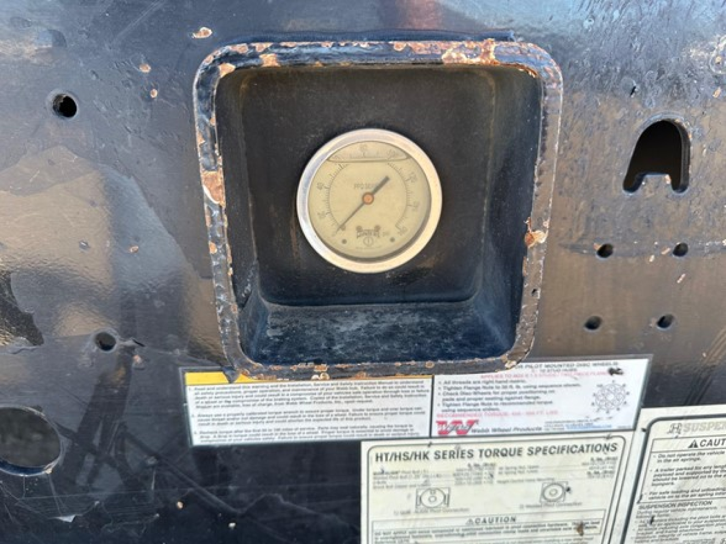 Hydraulic tail with upper deck trailer gauge and warning labels visible in a service bay.
