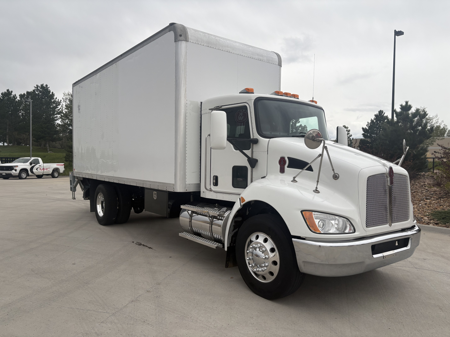 Kenworth T270 box truck in-service showing cab area and cargo box with dual rear wheels and chrome exhaust; windshield wipers and side mirrors visible.