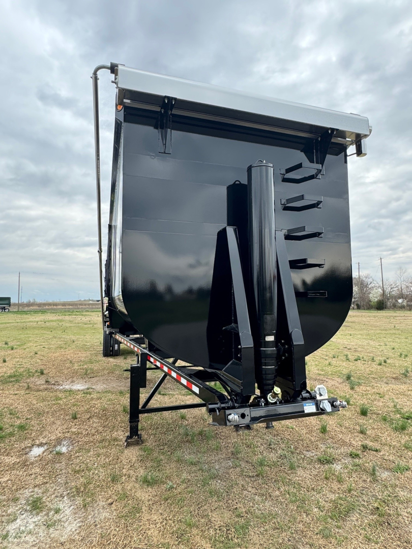 Dump trailer front view showing black Armor Lite 40' x 100" with raised gooseneck and hydraulic ram, dual axles not visible, white top edge.