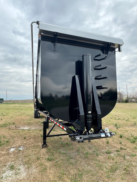 Dump trailer front view showing black Armor Lite 40' x 100" with raised gooseneck and hydraulic ram, dual axles not visible, white top edge.