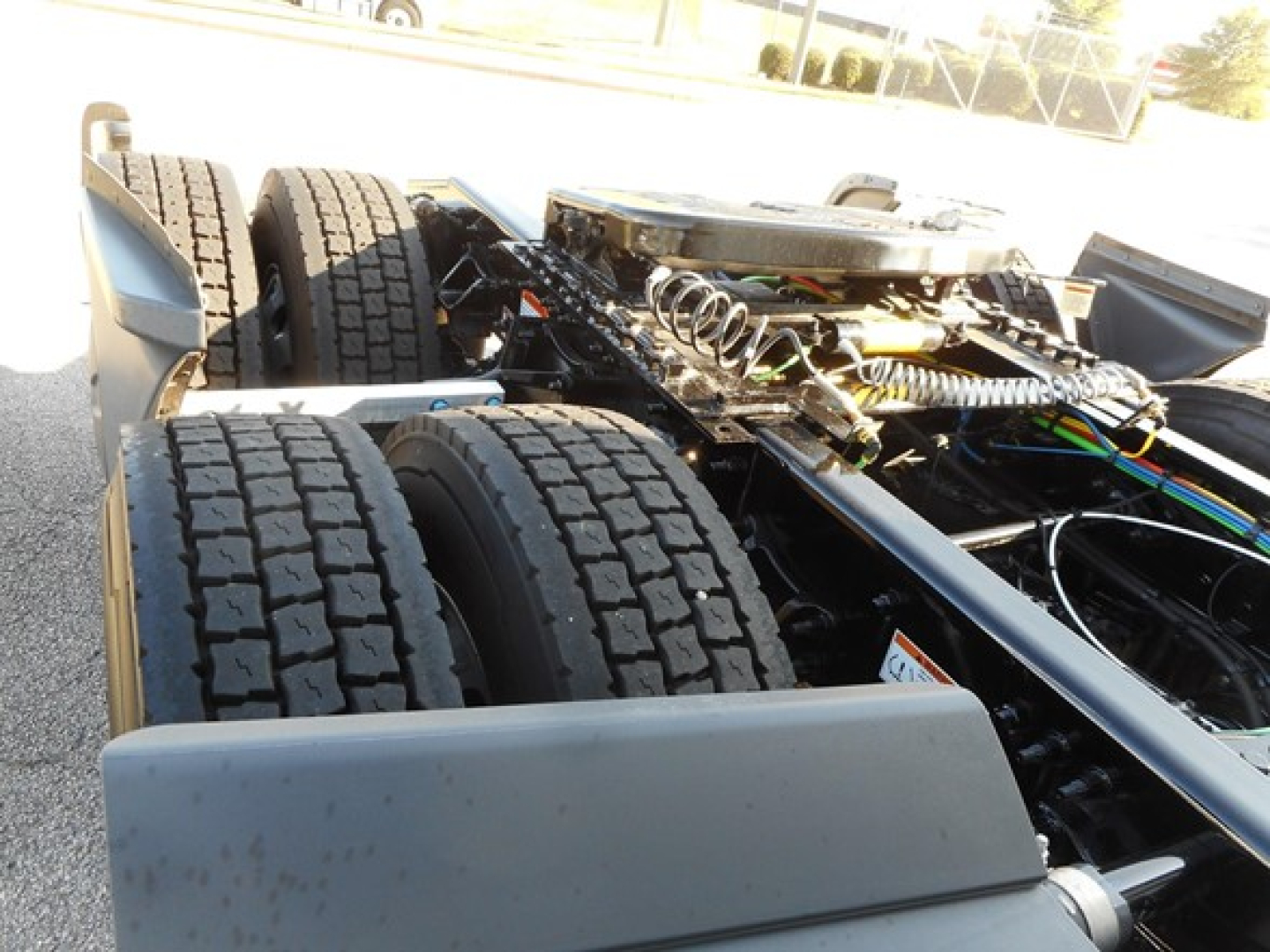 Freightliner Cascadia chassis showing dual rear axles with exposed drivetrain and wiring harnesses in the cabless area.