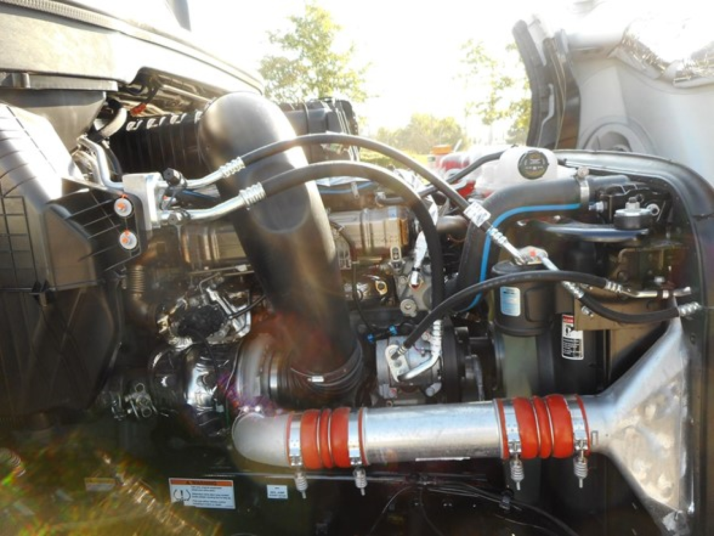 Freightliner Cascadia engine bay showing interconnected hoses, intake, and metal piping with red insulated section in foreground.