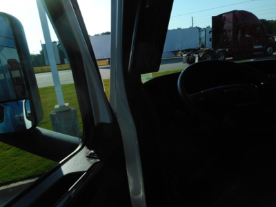 Freightliner Cascadia cab interior and side mirror from driver's door angle.
