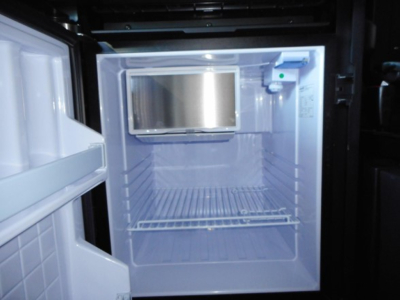 Freightliner Cascadia 126 truck interior showing empty refrigerator/freezer unit mounted in cab with shelves.