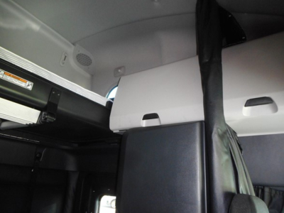 Truck cab interior showing bunk area and seat belt in a Freightliner Cascadia 126 sleeper cab with grey and black panels.