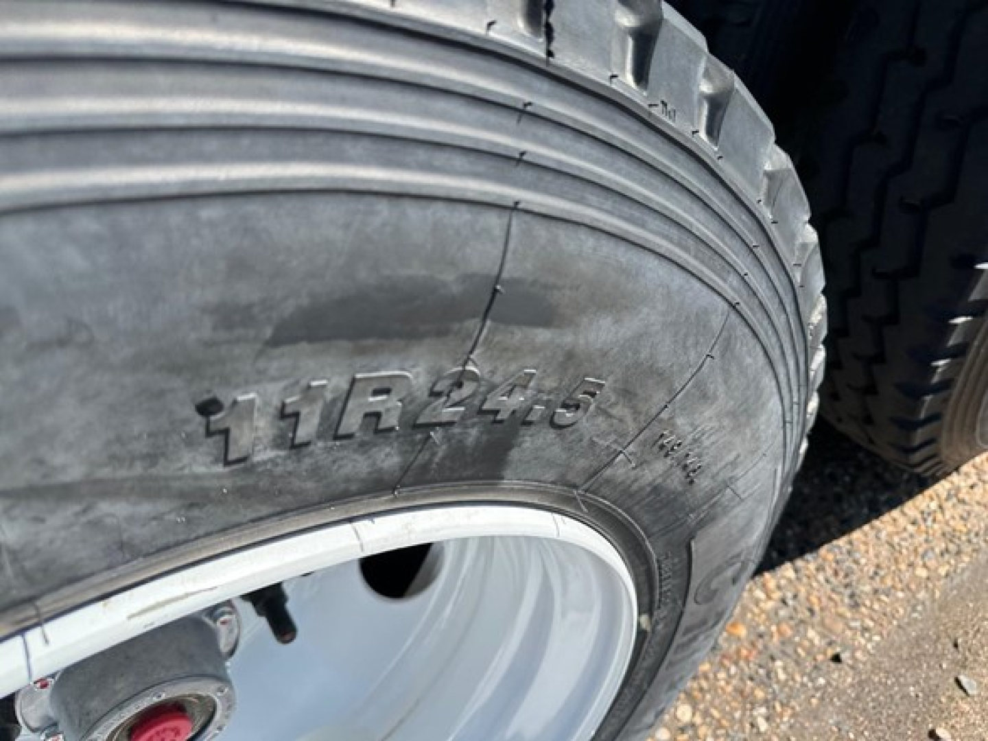 Tire close-up showing tire size 11R24.5 on a trailer wheel rim, with tread and wheel area visible.