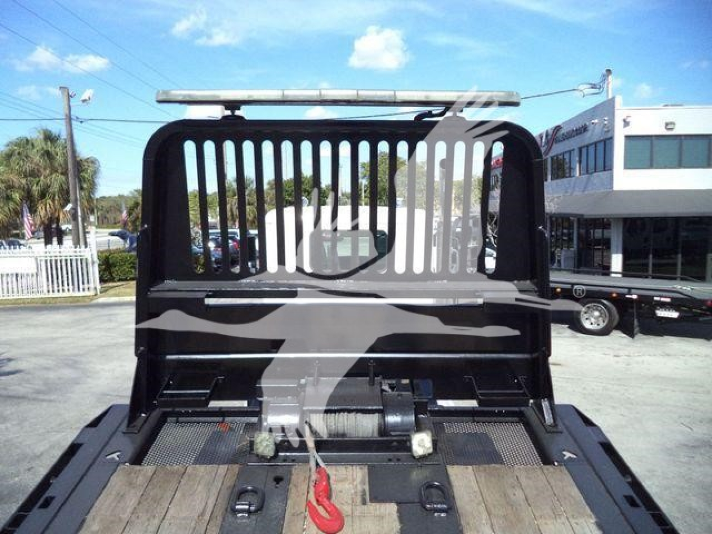Truck bed of a 2016 Peterbilt 567 rollback showing rear cabin bulkhead with protective grille and winch area.