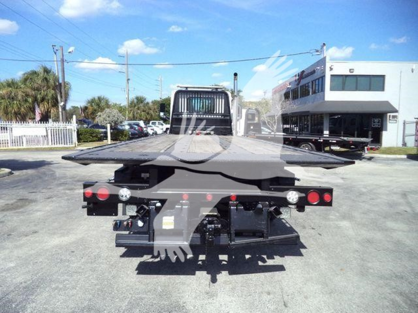 Rear view of a 2016 Peterbilt 567 rollback w/ flatbed carrier and twin taillights in a dealership lot.