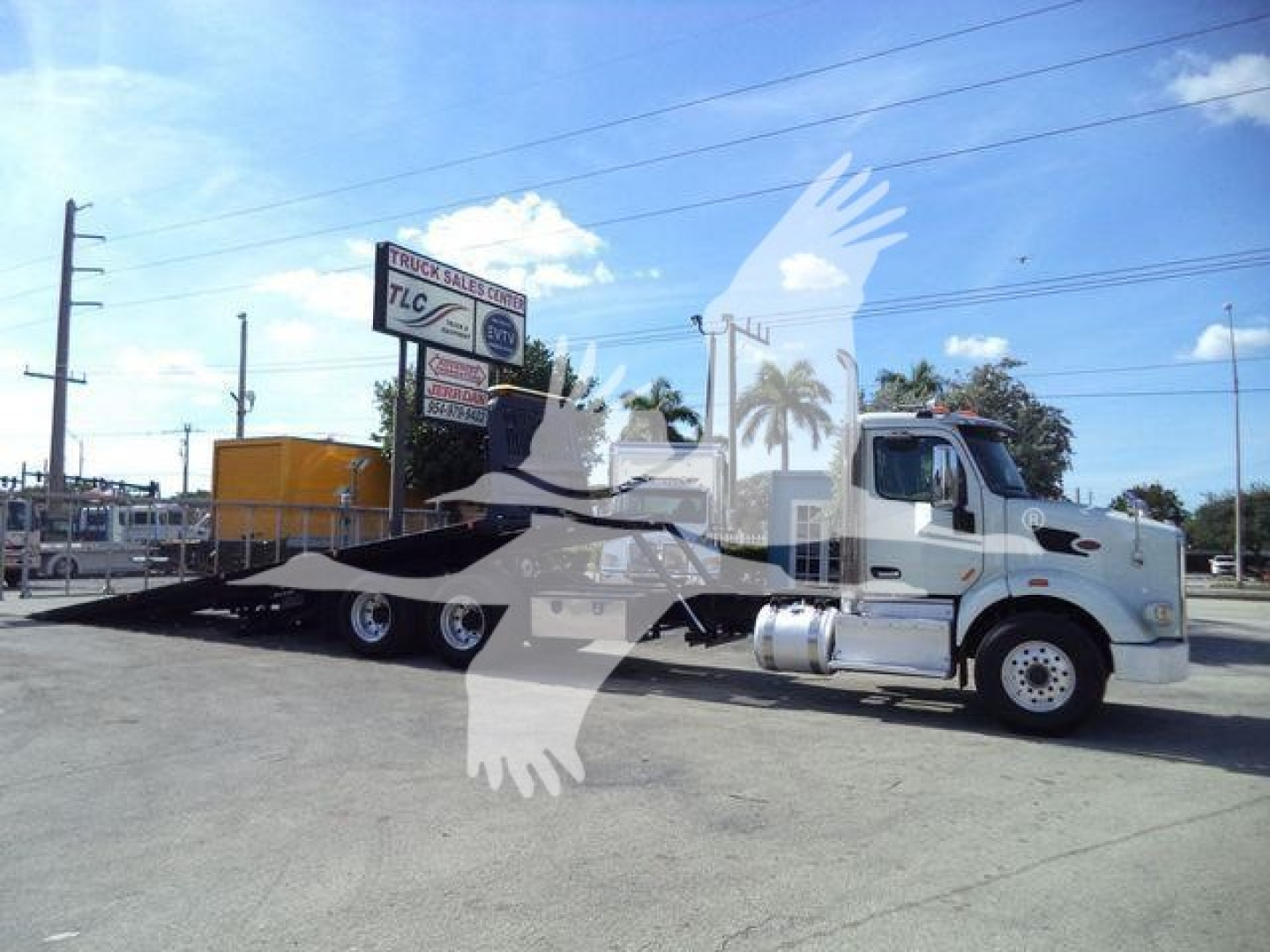 Truck: 2016 Peterbilt 567 rollback tow truck in light color with flatbed trailer and chrome fuel tanks, side view