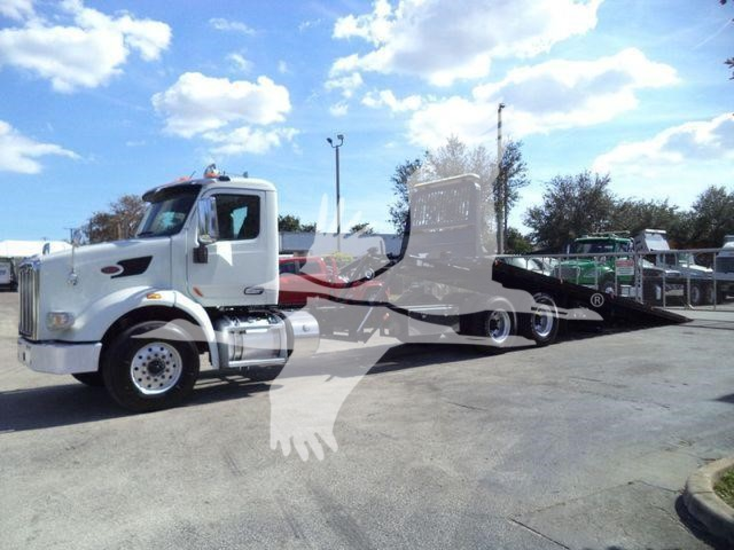 2016 Peterbilt 567 rollback tow truck in a lot, side view shows cab and flatbed hydraulic rollback equipment.