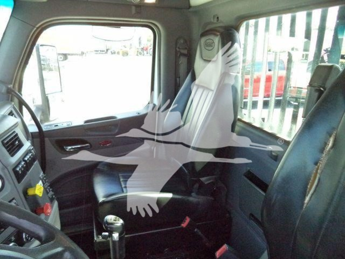 Truck cab interior of a Peterbilt 567 with dashboard controls, steering wheel, and passenger seat visible through the window, stock image style.