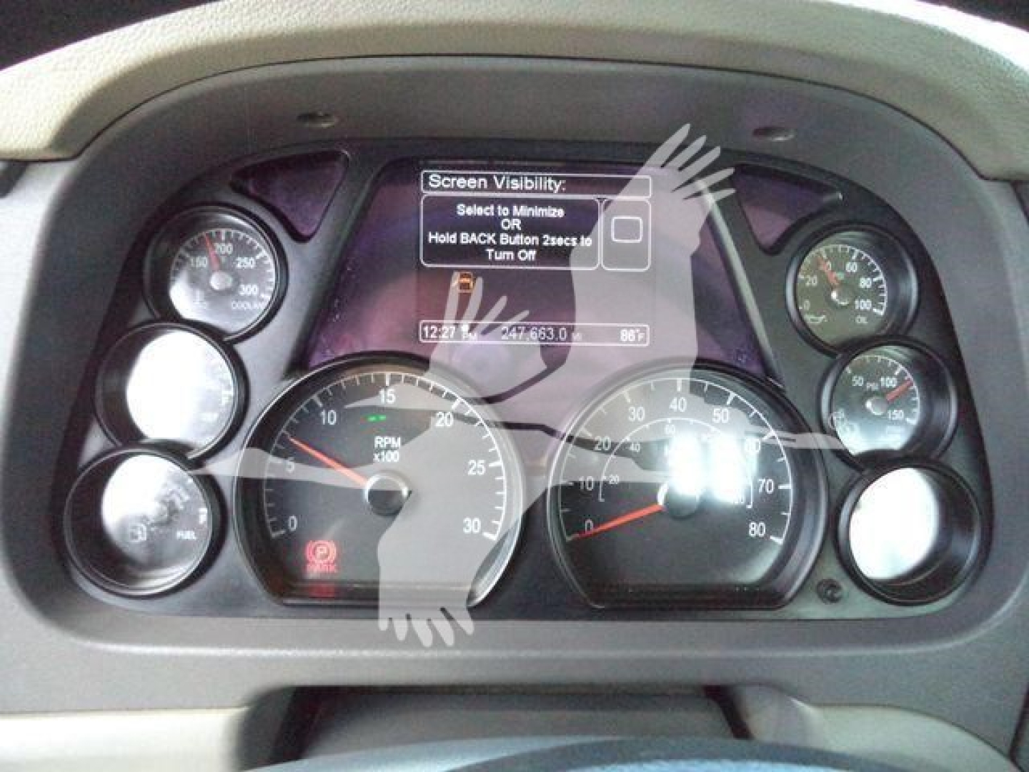 Instrument cluster of a Peterbilt 567 dashboard with multiple gauges and a central display screen.