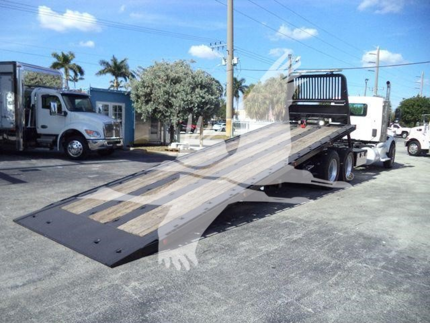 Peterbilt 567 rollback tow truck with a tilted ramp bed in a dealership lot; no readable labels or serials on the truck are legible in this view.