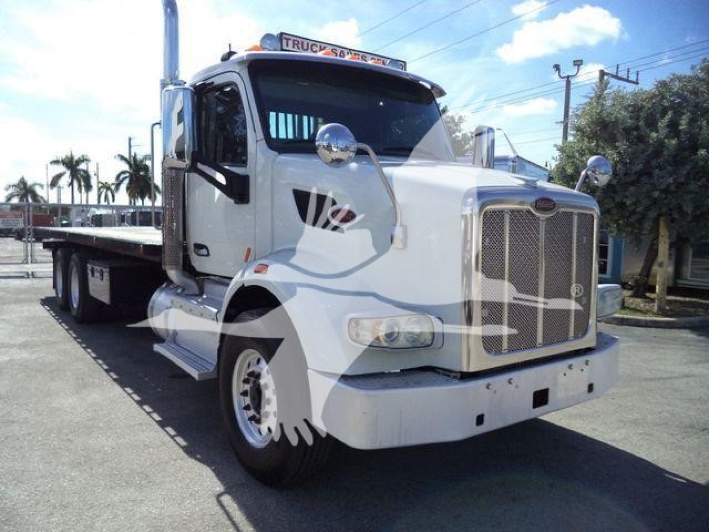 Peterbilt 567 truck in white, front three-quarter view with flatbed rollback, chrome grille, dual mirrors, and Peterbilt badge visible.