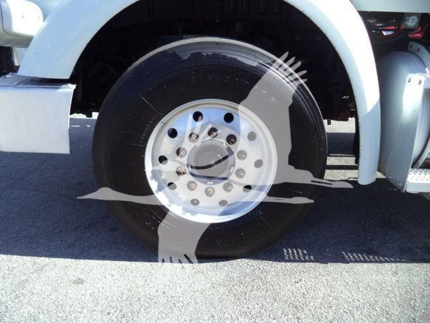 Truck wheel with silver rim and black tire; part of white Peterbilt 567 cab visible; no readable labels or numbers.