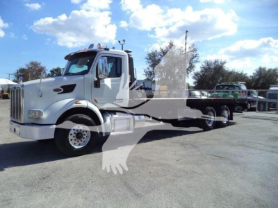 Peterbilt 567 rollback tow truck in white with flatbed, side view showing cab and chassis; stock number T01476FM partially visible in listing.