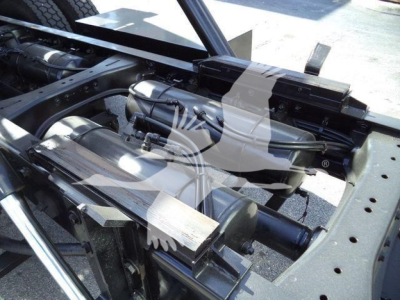 Tractor-trailer truck drivetrain components visible in the chassis of a Peterbilt 567, with drive shaft and air tanks in view.