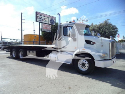 Peterbilt 567 highway truck side view showing flatbed rollback with white cab and chassis.