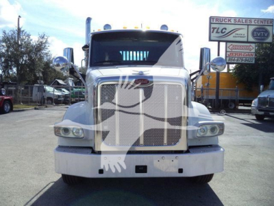 Peterbilt 567 grille and front view of a used truck in a dealership lot with chrome mirrors and large bumper.