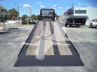 Peterbilt 567 rollback truck shown from rear of ramp bed, flatbed with wooden planks and steel edges.