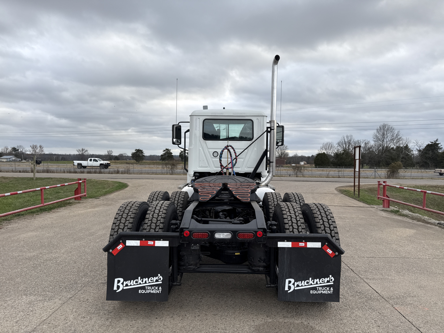 Rear view of a new 2026 Mack PI64T conventional daycab truck showing dual rear wheels and mud flaps with Bruckner's Equipment logos.