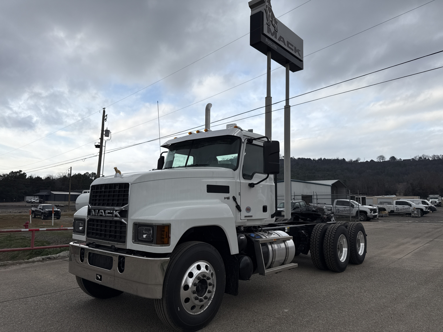 Mack PI64T conventional daycab truck in white, angled side view showing front grille, bumper, dual rear axles, and fuel tanks.