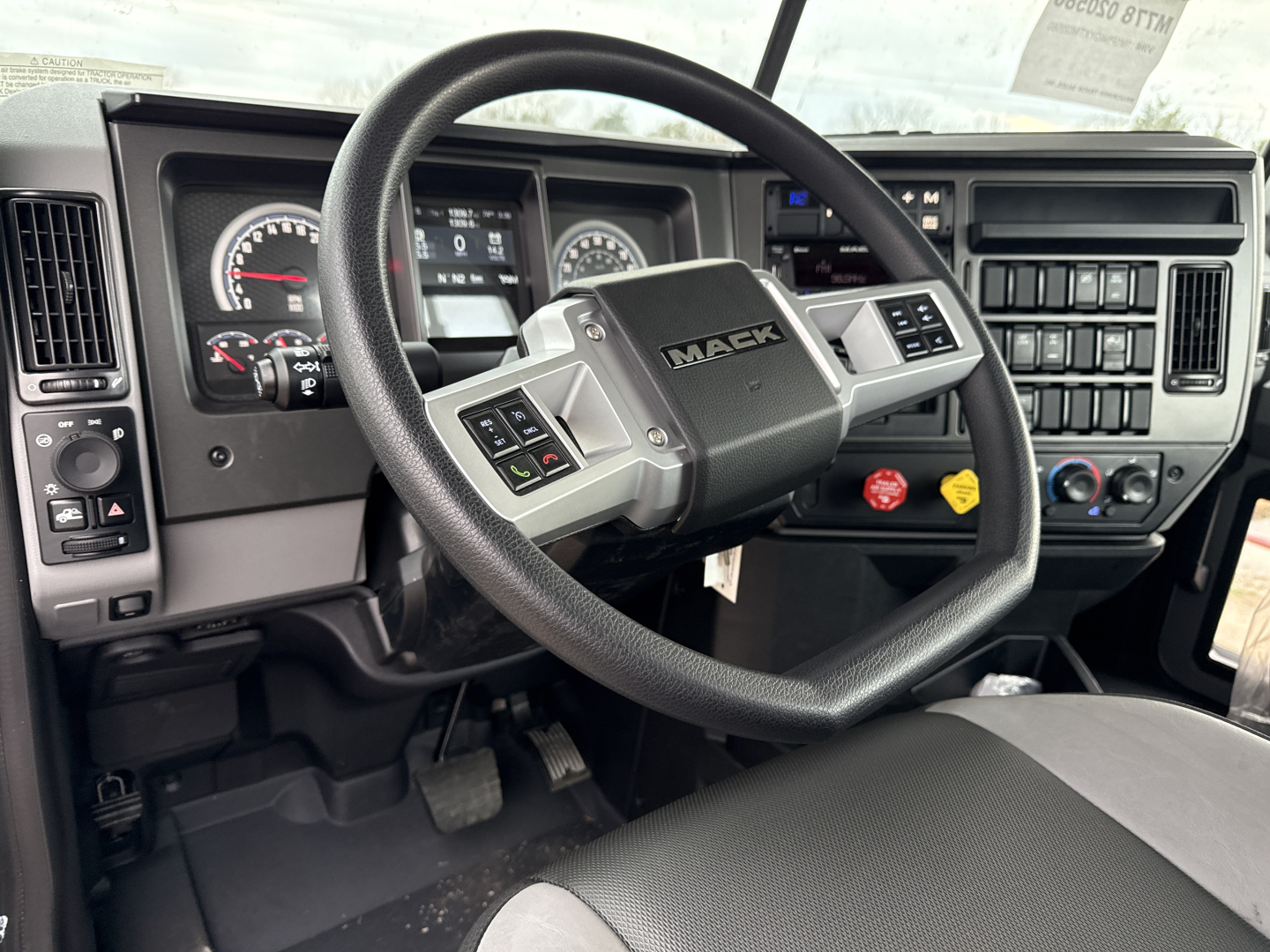 Mack PI64T truck interior showing steering wheel and gauge cluster with center console and controls.
