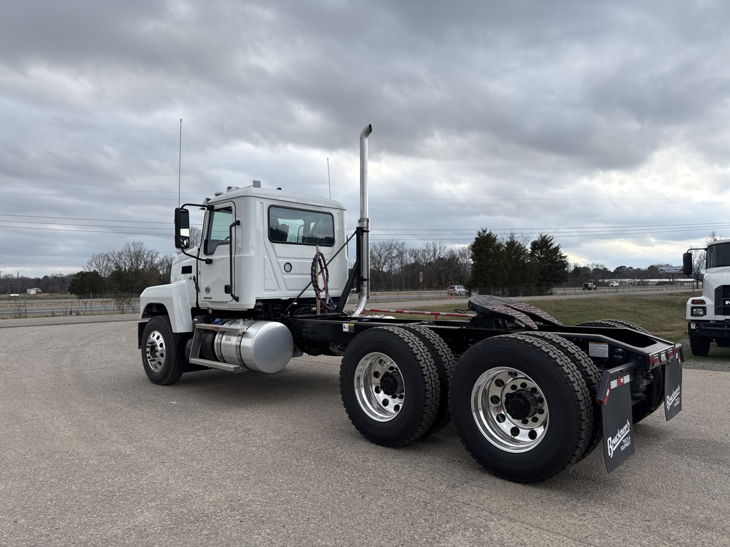Mack PI64T truck tractor rear and cab side view showing dual rear axles, fuel tanks, and exhaust stack with chrome finish.