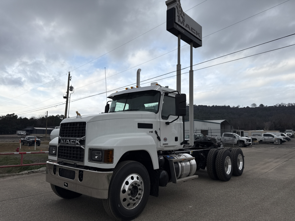 Mack PI64T conventional daycab truck in white, angled side view showing front grille, bumper, dual rear axles, and fuel tanks.