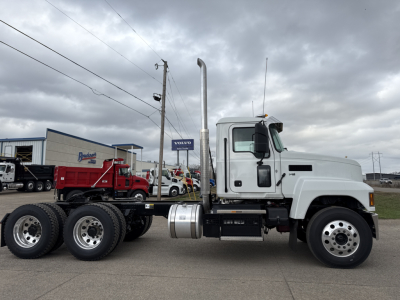 Truck side view of a 2026 Mack PI64T conventional daycab, white cab, chassis with dual rear axles, fuel tanks under cab, tall exhaust stack, VIN 1M1PN4GY5TM020583 visible in listing context.