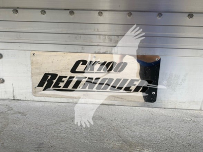 CK100 Reitnouer trailer plate with CK100 logo mounted on aluminum side panel, flatbed trailer branding.