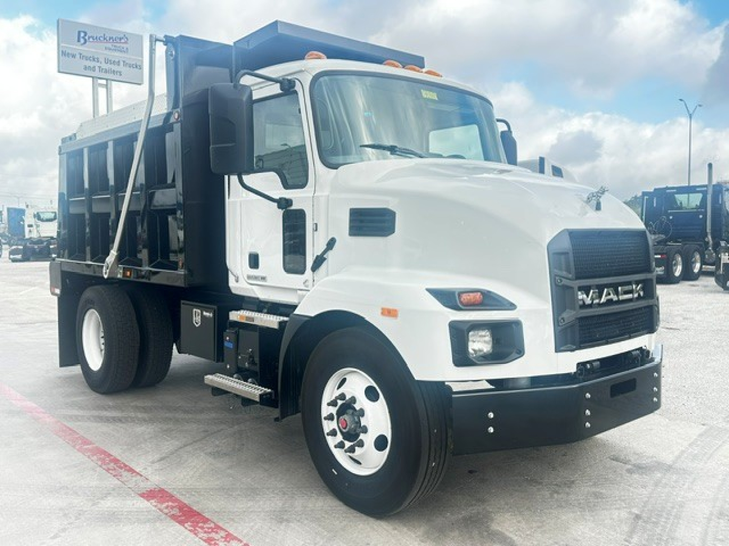 Mack MD7 dump truck in white with black grille showing cab, front view, and dump bed.