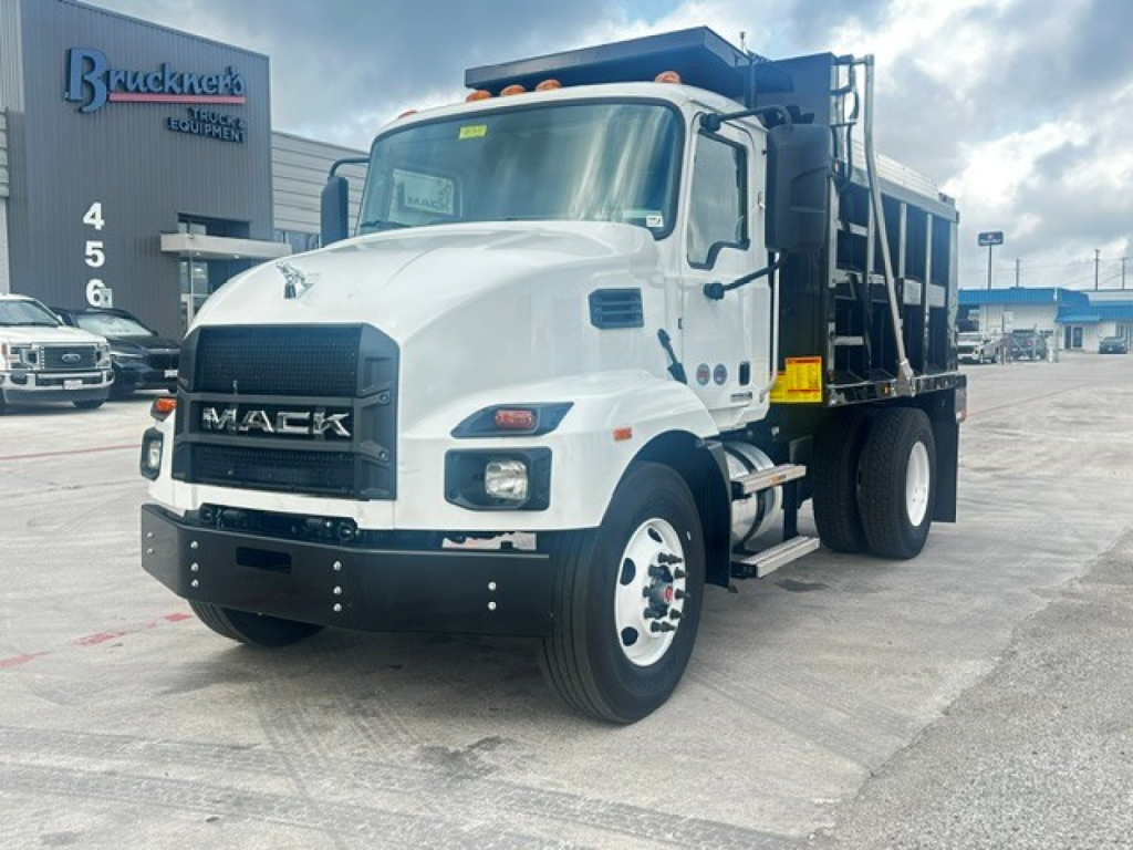 Mack MD7 dump truck in white and black, front-left view showing large grille, bumper, dual rear wheels, and hydraulic dump bed.