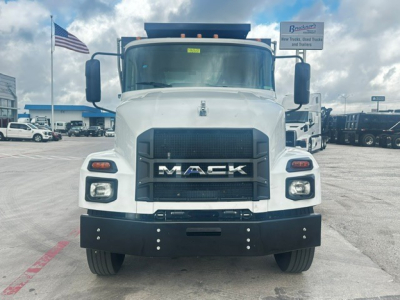 Front view of a white Mack MD7 dump truck showing grille with MACK emblem and bumper, with headlights and side mirrors visible.