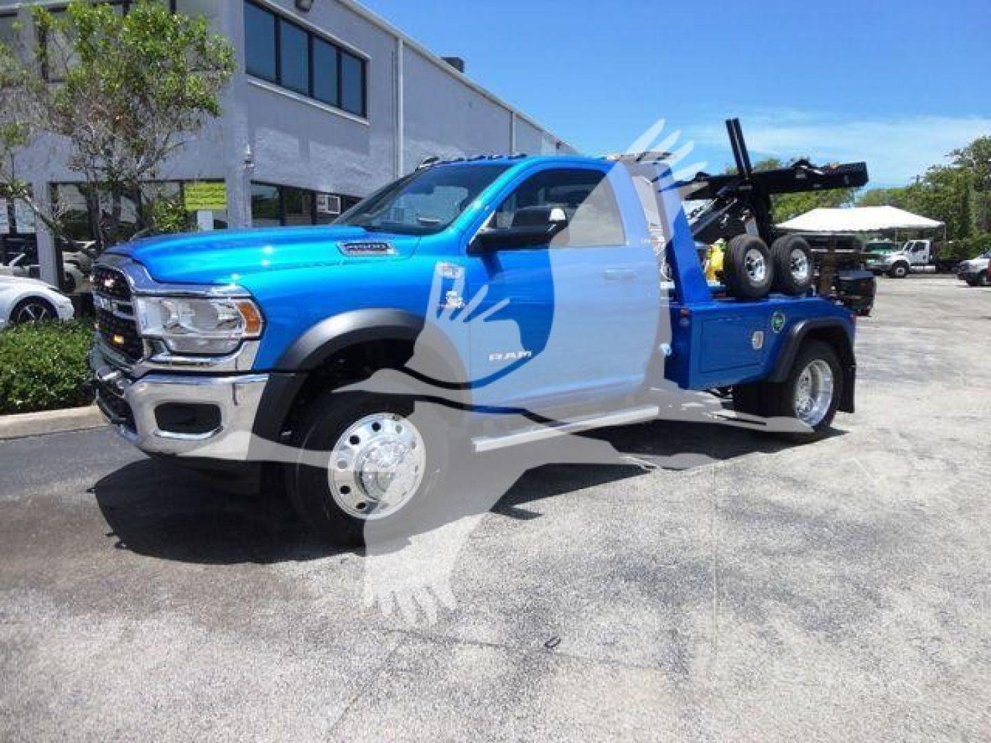 Ram 4500 tow truck with blue and gray graphics, side view showing extended cab and winch equipment in bed.