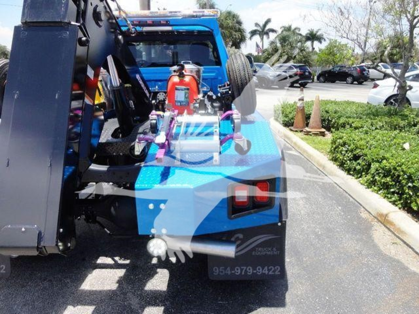 Ram 4500 SLT winch-equipped pickup truck rear view showing external winch gear and spare tire, blue body with black bumper, dealership lot in background.