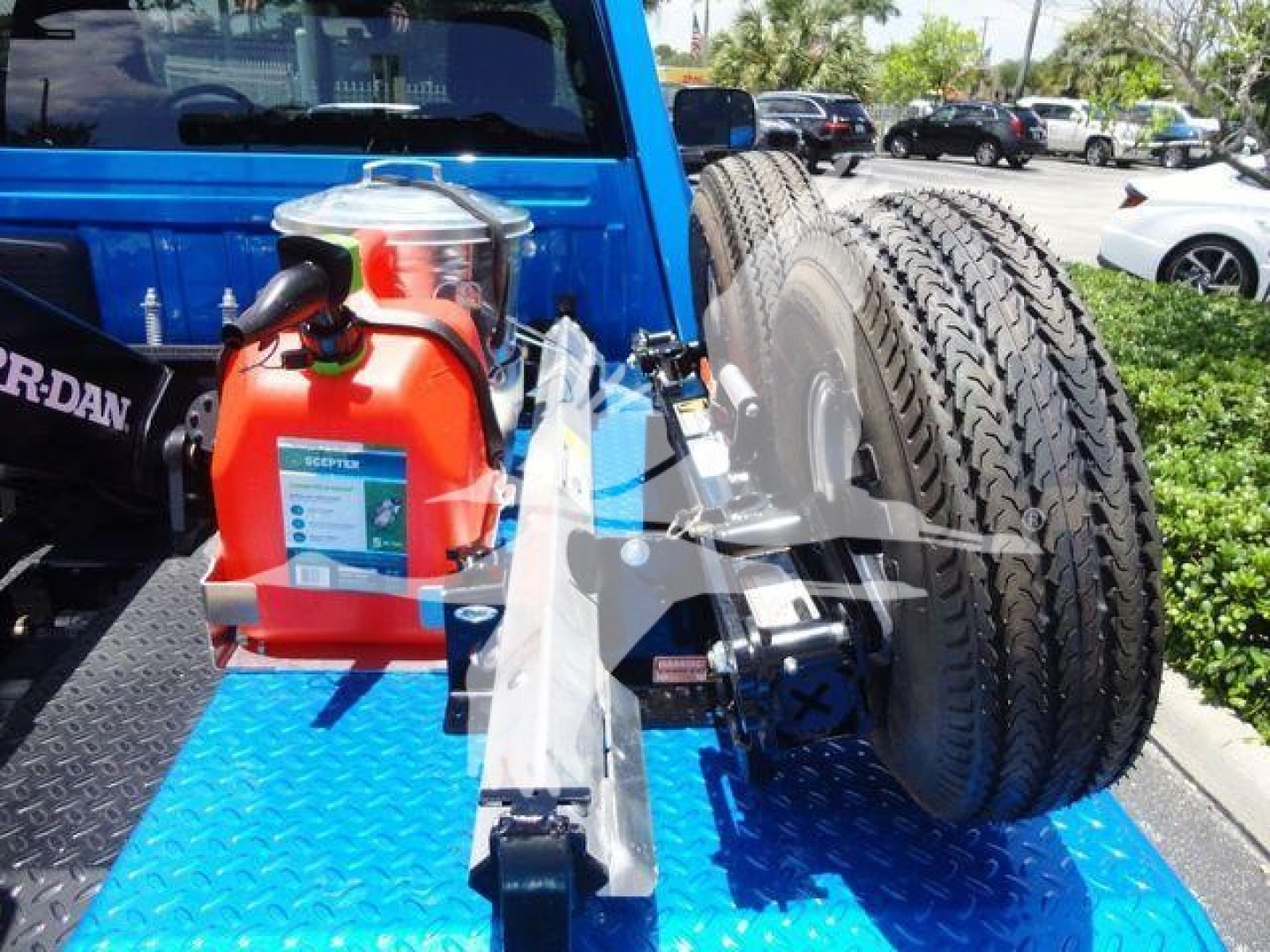Truck bed showing a winch setup with a red portable winch and large off-road tires mounted on the flatbed.