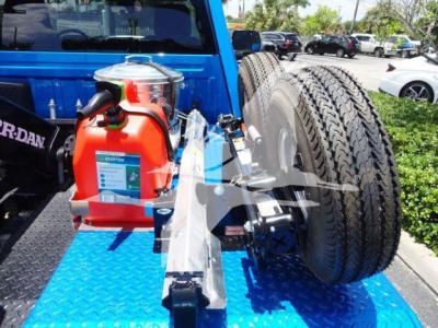 Truck bed showing a winch setup with a red portable winch and large off-road tires mounted on the flatbed.