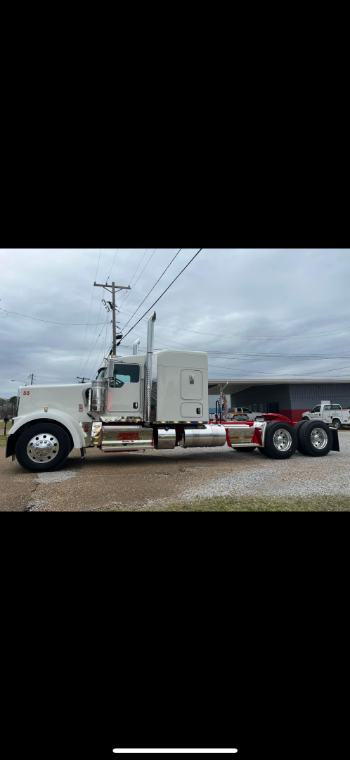 Kenworth W900L conventional sleeper truck side view showing long cab, dual rear axles, chrome exhaust stacks, and white/cream color.