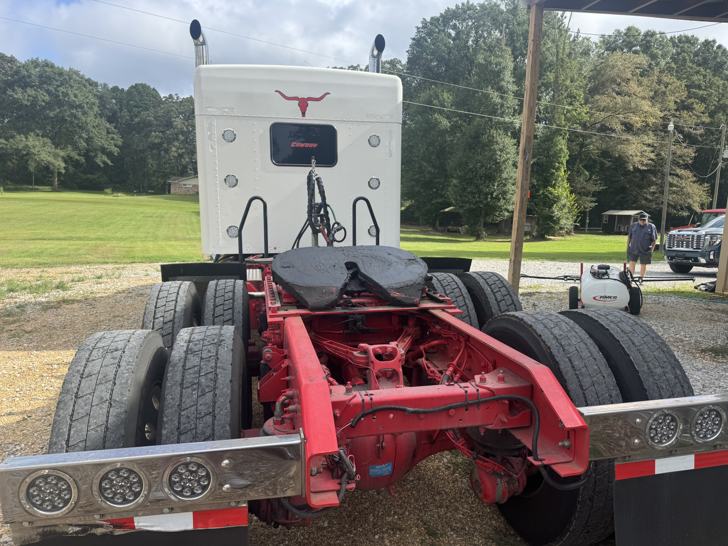 Kenworth W900L truck chassis rear view showing fifth wheel, red chassis, dual rear axles, and dual rear tires.