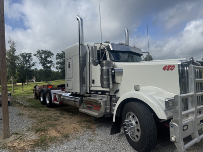 Kenworth W900L conventional sleeper truck in white with large chrome exhaust stacks and 450 badge on fender, side view showing chrome bumper and dual rear wheels.