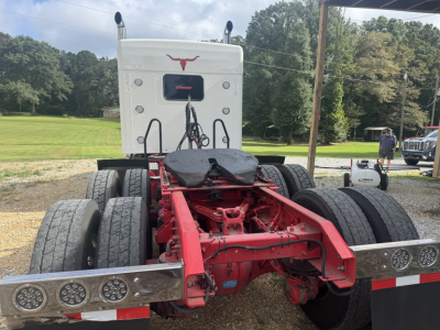 Kenworth W900L truck chassis rear view showing fifth wheel, red chassis, dual rear axles, and dual rear tires.
