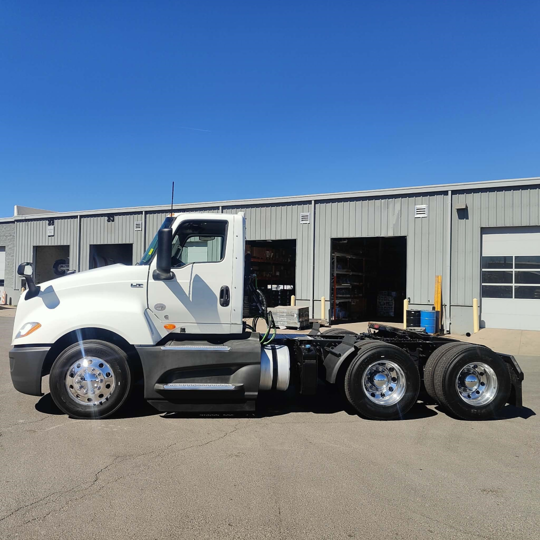 Truck chassis of a white 2021 International LT daycab, side view showing a cab with dual rear axles and chrome wheels.