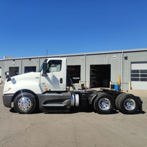 Truck chassis of a white 2021 International LT daycab, side view showing a cab with dual rear axles and chrome wheels.
